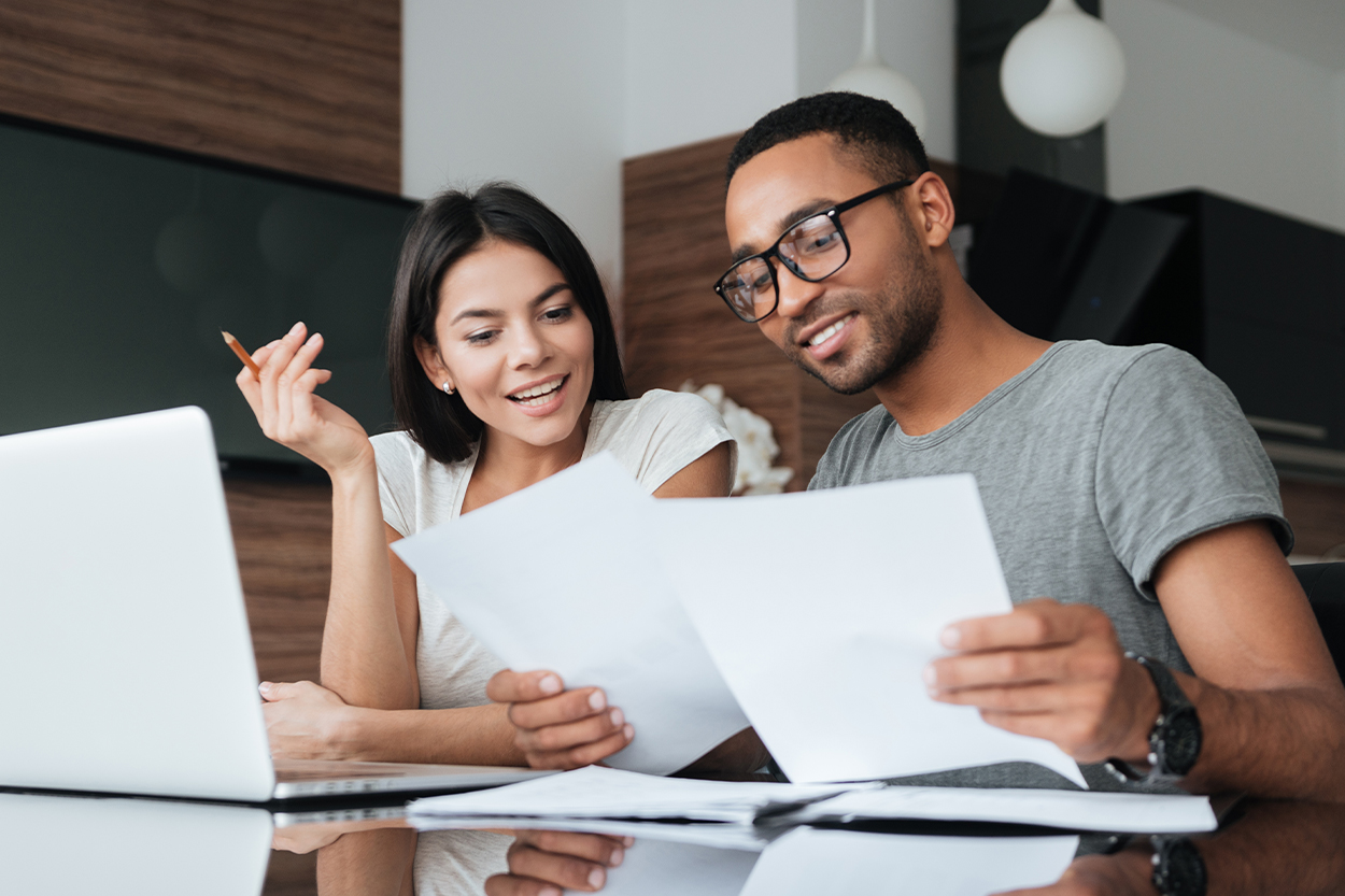 Young couple with laptop reviewing paperwork