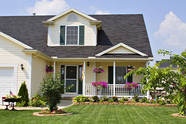 White suburb home with plants and flowers in the yard