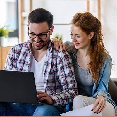 Couple smiling, researching on laptop