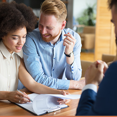 Young couple signing mortgage paperwork with realtor