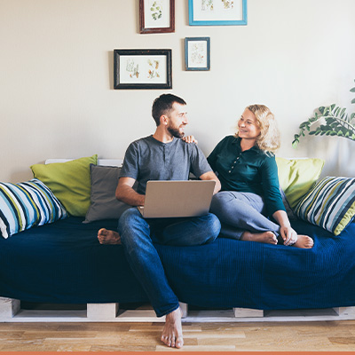 Happy young couple on couch with laptop