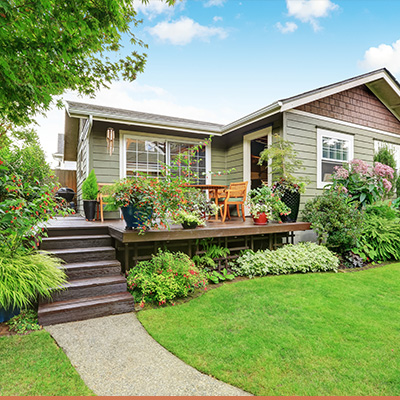 Front porch of cottage style house with plants and greenery on deck