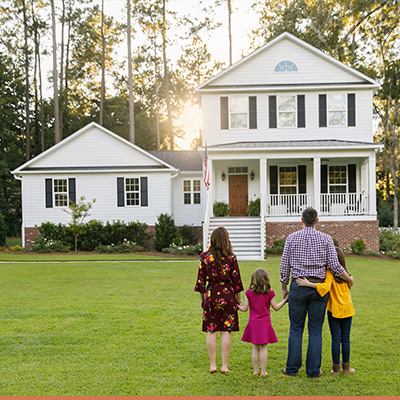 Young family standing outside of farm house