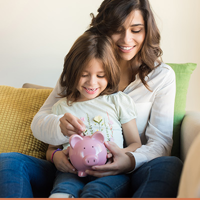 Young mom and her daughter holding piggy bank