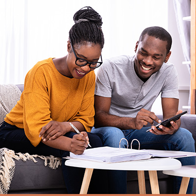 Couple sitting on couch filling out paperwork smiling