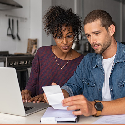 Young couple on laptop reviewing paperwork