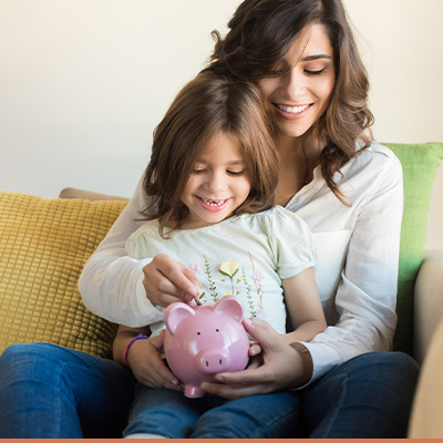 Young mom with her daughter holding a piggy bank