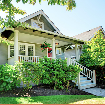 House with white front porch and plants in yard