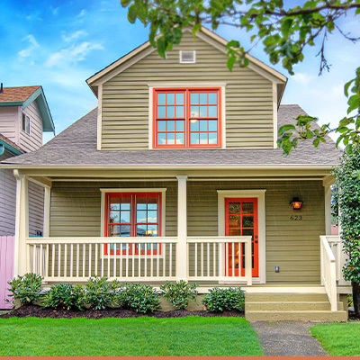 Tan house with red window trim. Vibrant colors in summer season.