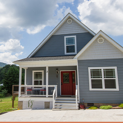 Exterior two story cottage style house with blue sky and clouds