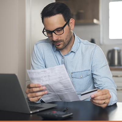 Young man reviewing credit report holding credit card