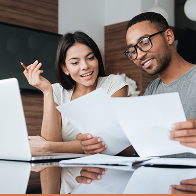 Young couple looking at papers and laptop smiling