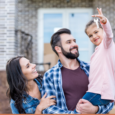 Young happy family outside new house holding the key