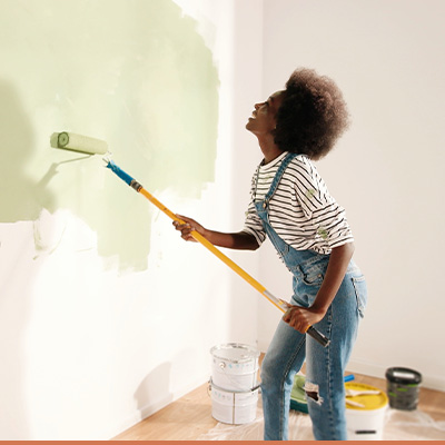 Young African American woman painting interior walls green