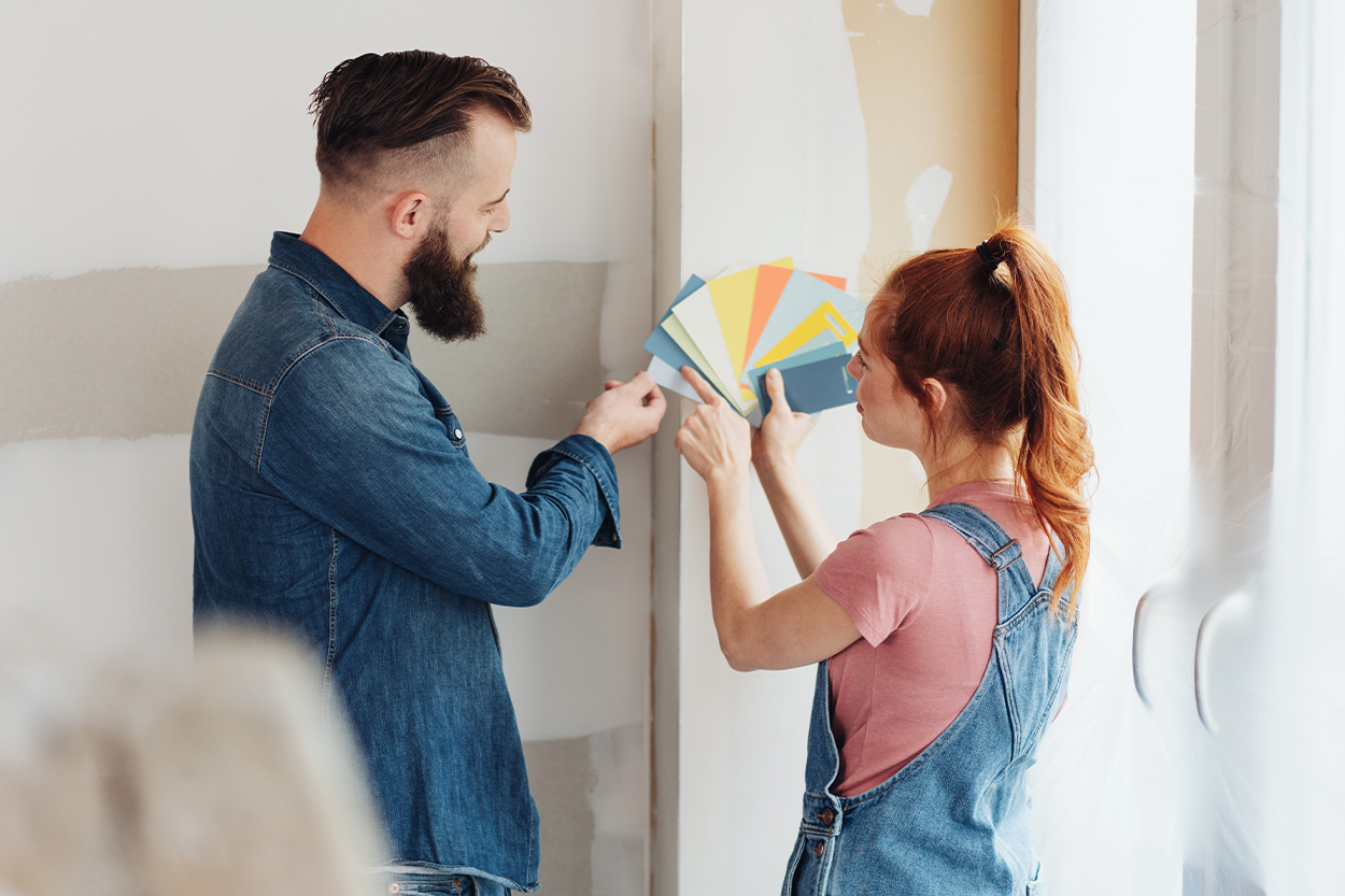 Couple holding paint swatches against wall