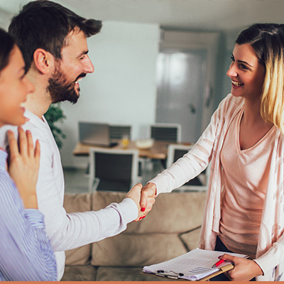 Young couple in house shaking hands with realtor