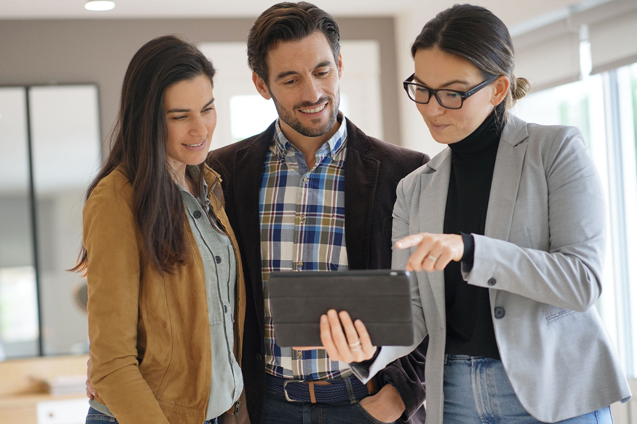 Couple looking at ipad with realtor in home