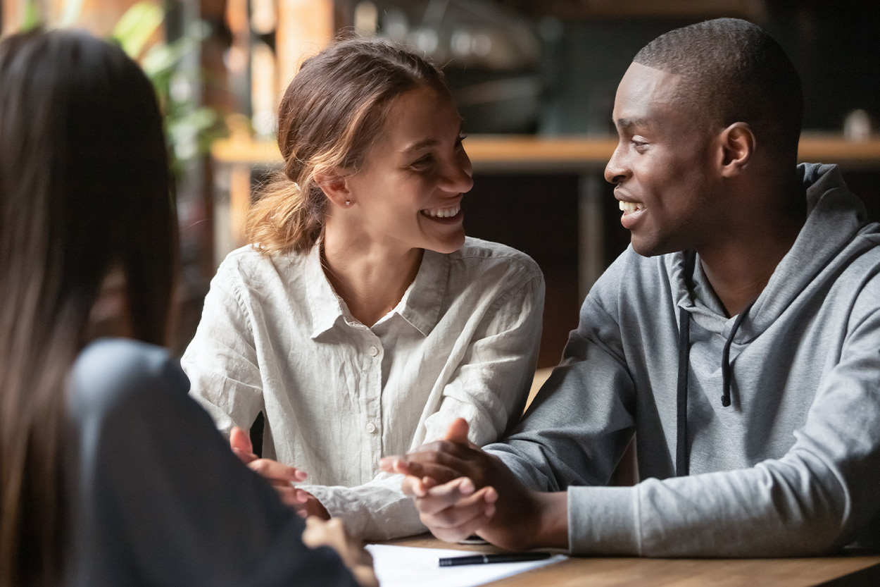 Young Couple smiling at each other at a table with their agent