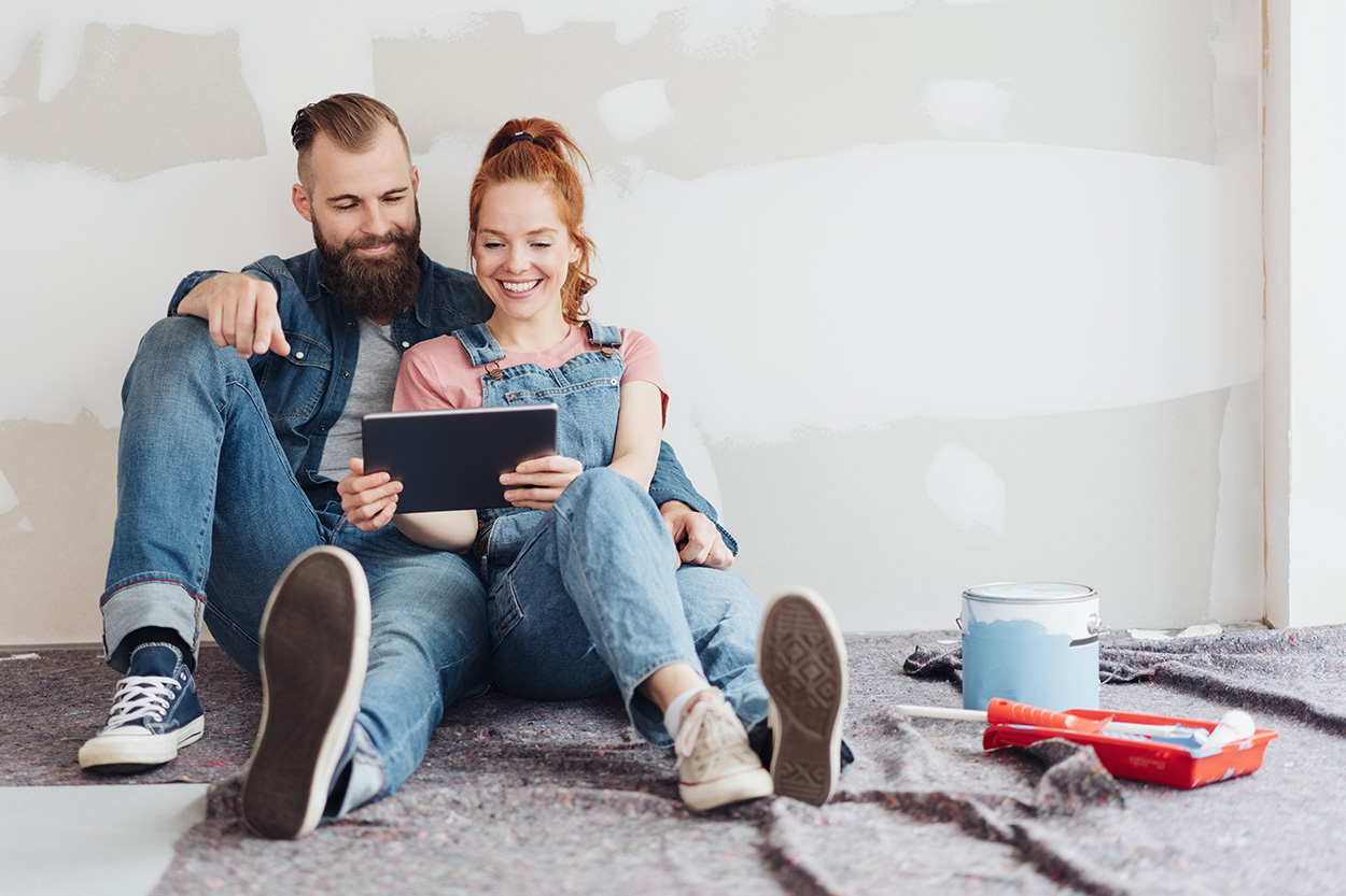 Couple sitting in room under construction watching ipad