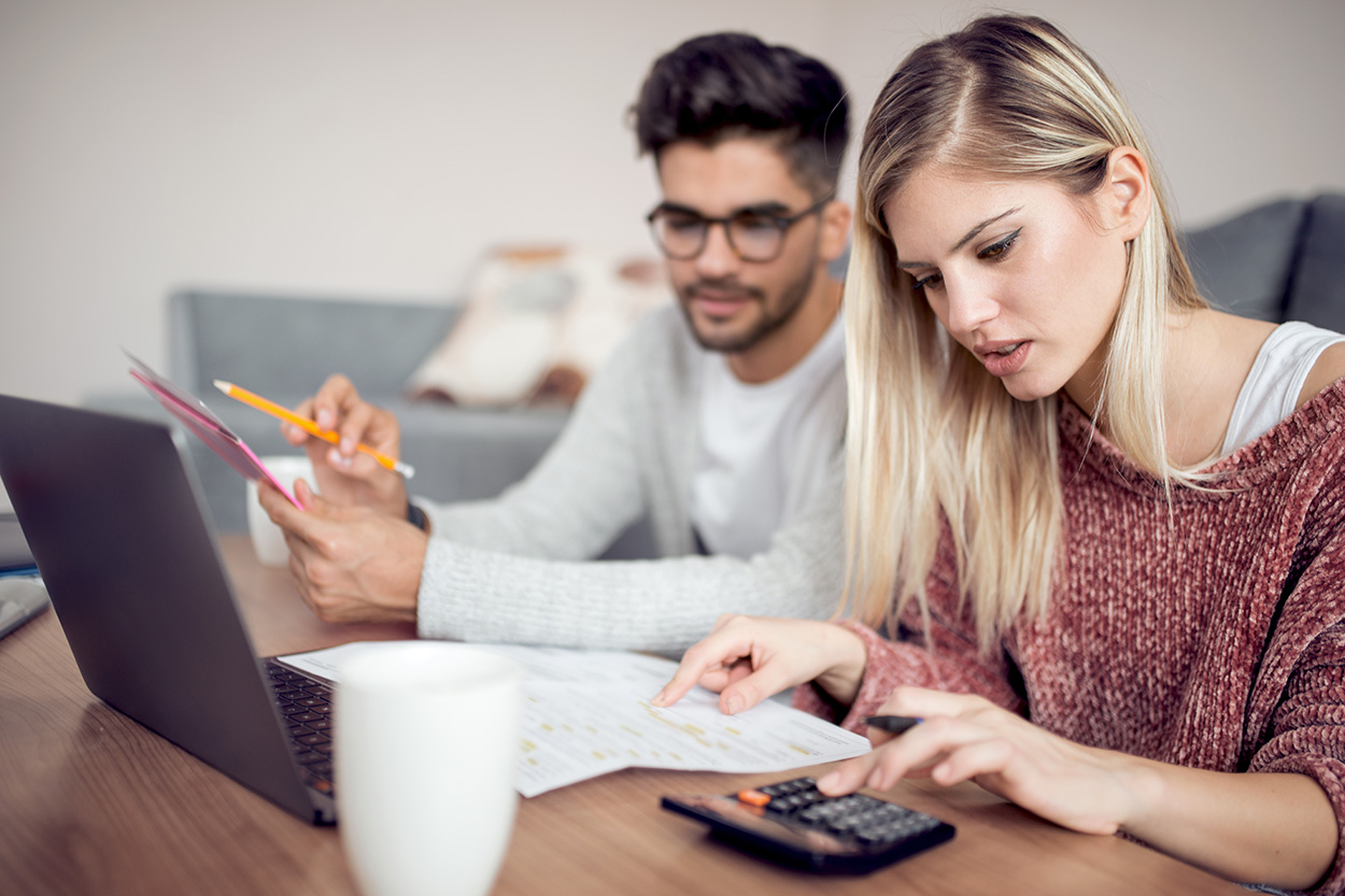 Young couple reviewing finances with calculator and paperwork