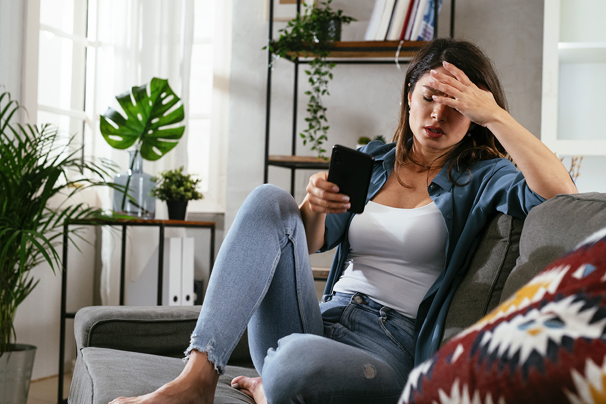 Women on couch stressed out looking at her phone