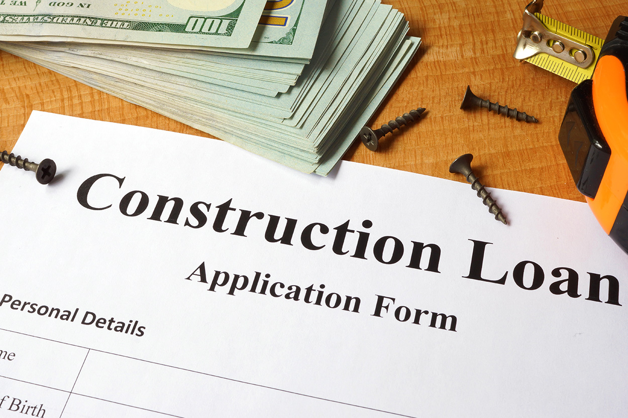 paperwork for construction loan with cash and nails on counter