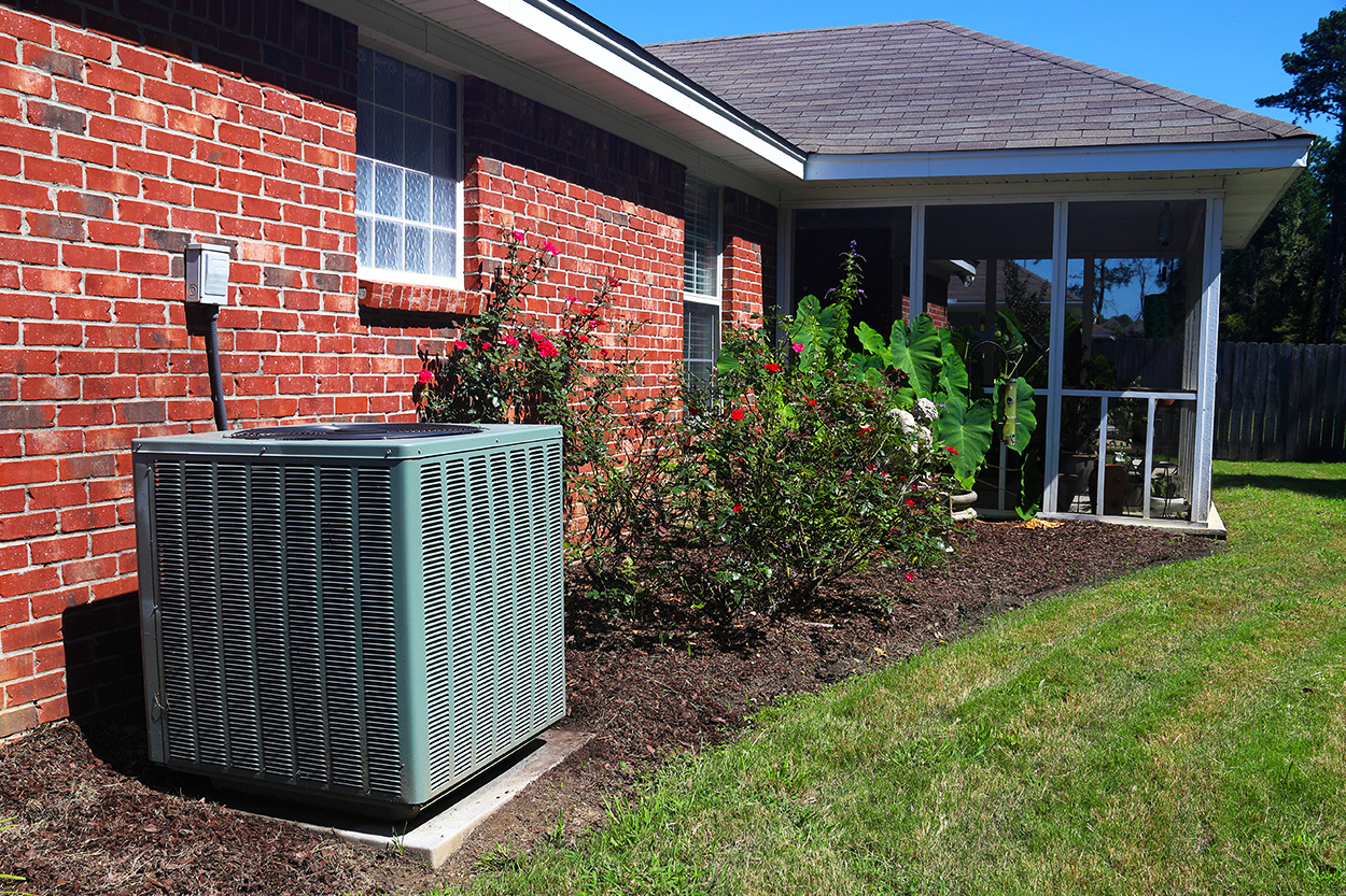 Central Air Conditioning unit outside brick house with porch