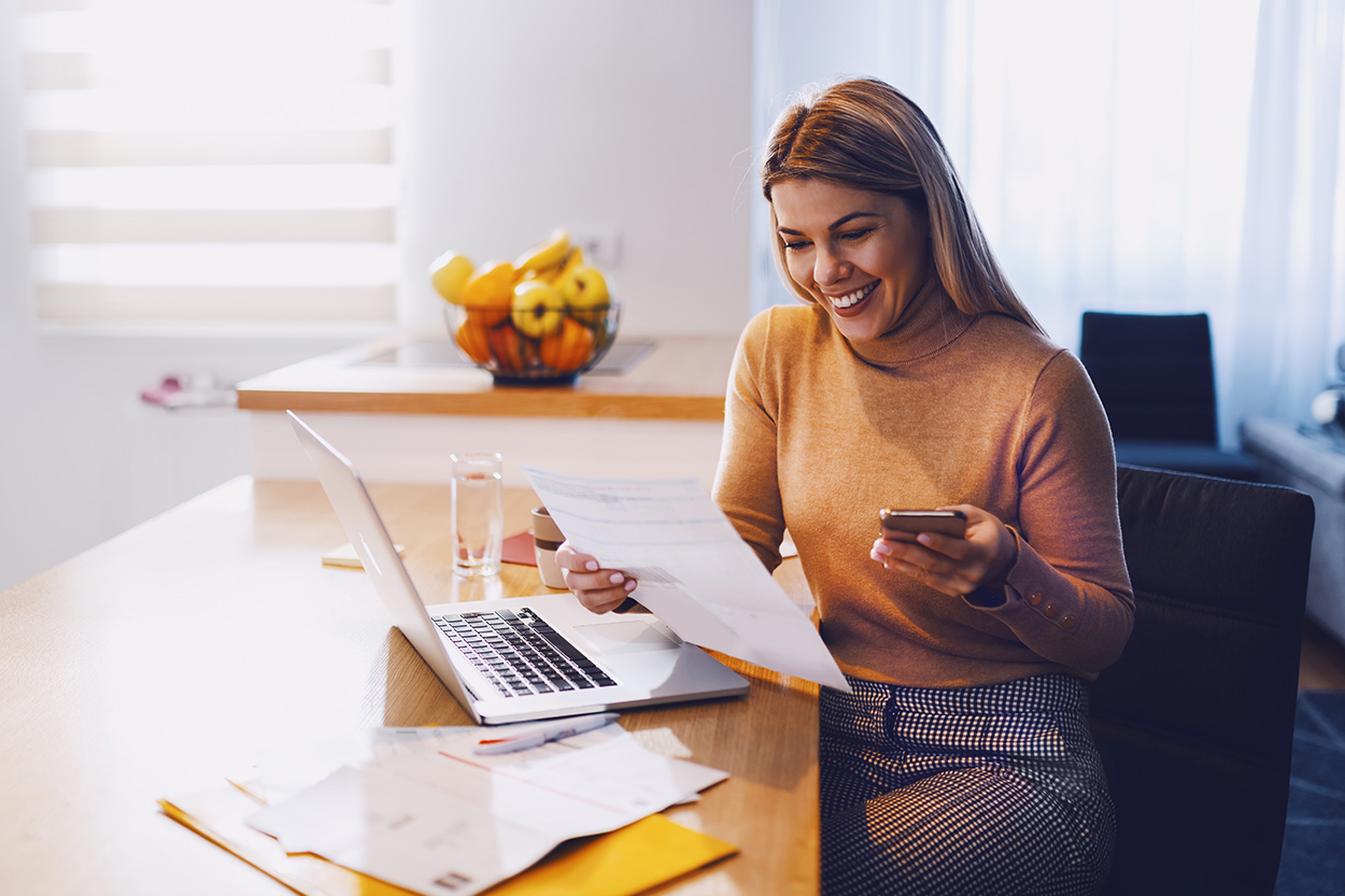 Young woman reviewing paperwork at home smiling