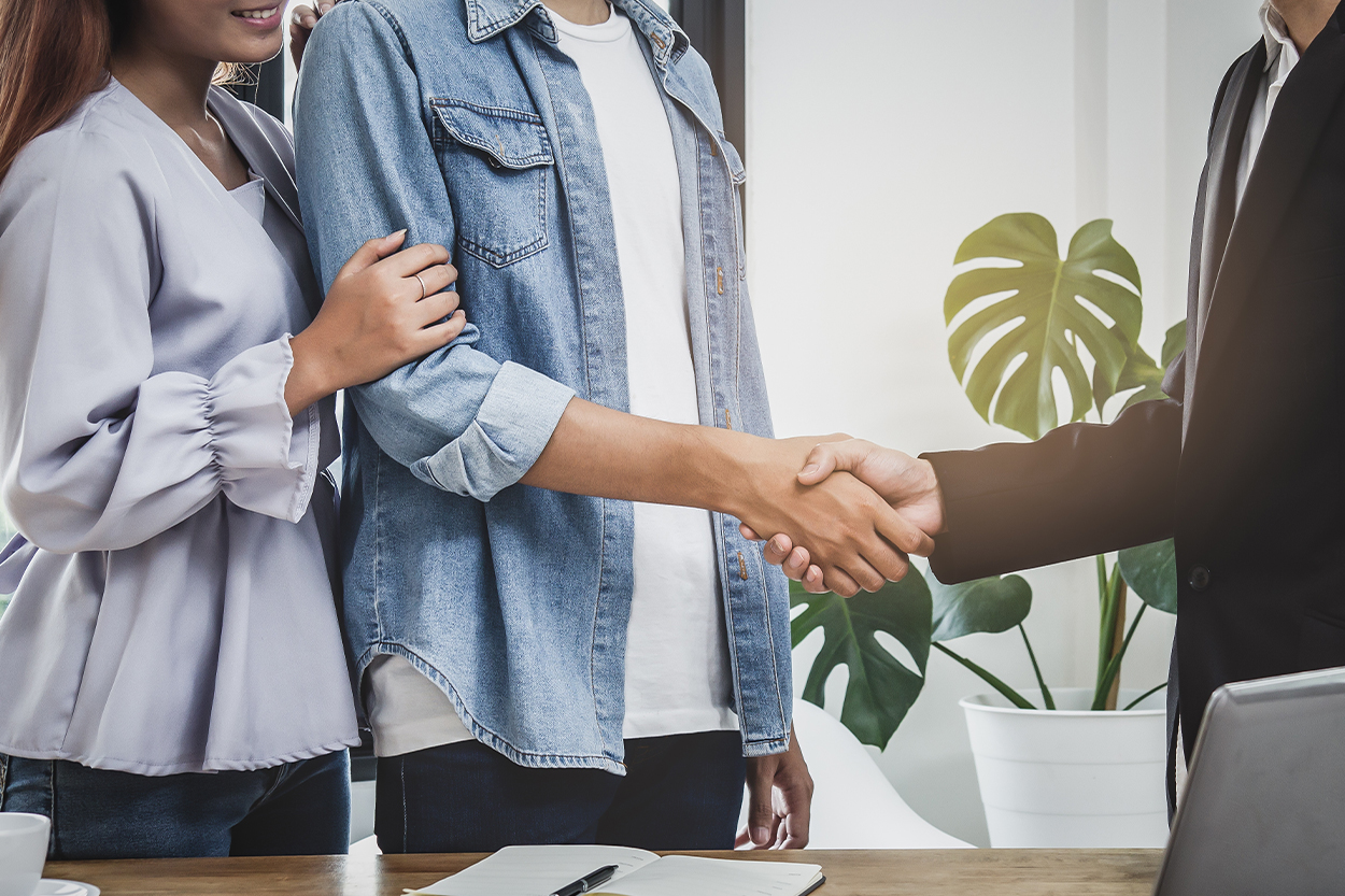 buyer and seller shaking hands with contract on table